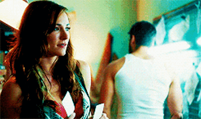 a woman in a tank top is holding a card in her hand