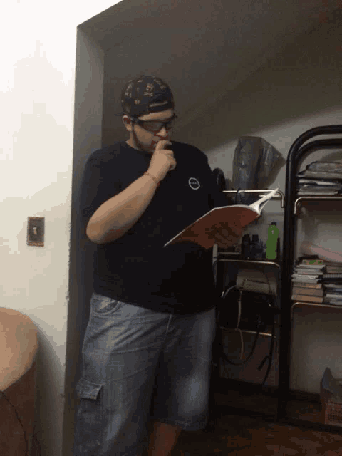 a man wearing a hat and glasses is reading a book in a closet