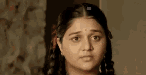 a close up of a woman 's face with a serious look on her face and braids in her hair .