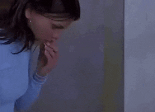 a woman with dark hair is wearing a blue turtleneck sweater and earrings .