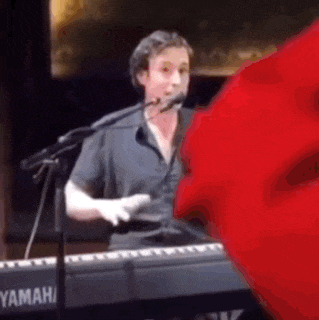 a man is singing into a microphone while playing a keyboard .