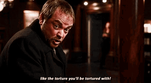 a man in a black suit and tie is talking to another man .