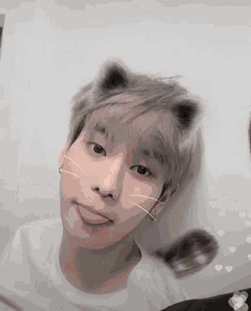 a young man wearing cat ears sticking his tongue out .