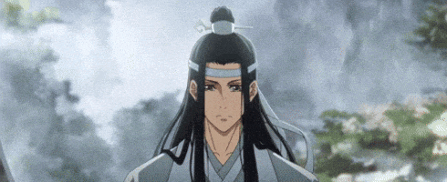 a man with long black hair and a blue headband is standing in front of a mountain .