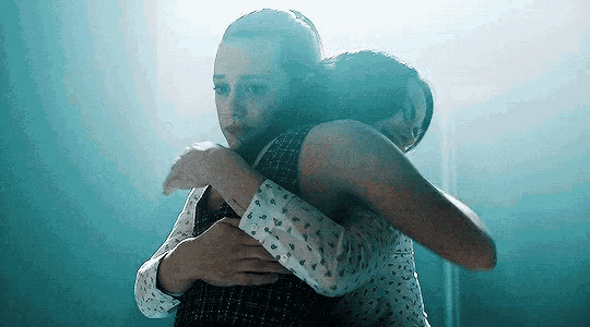 a couple of women hugging each other in a dark room