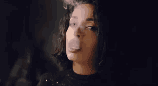 a woman is blowing a bubble with her mouth while smoking an electronic cigarette .