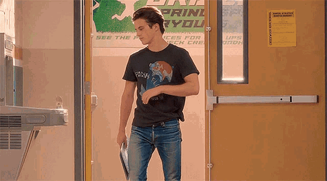 a man in a black t-shirt is standing in front of a door with a sign on it that says print you