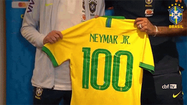 a man is holding a yellow and green soccer jersey with the name neymar jr. on it .