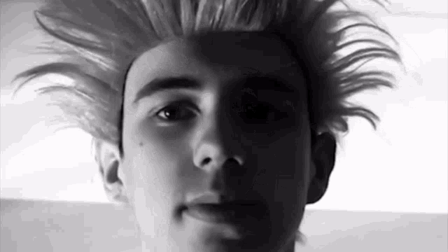 a black and white photo of a young man 's face with a wig on .