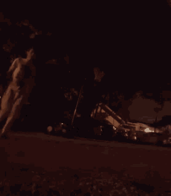 a person is walking down a street at night with a basketball in their hand .