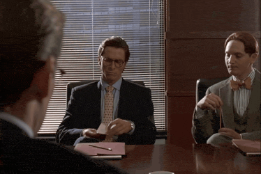 a man in a suit and tie is sitting at a table with two other men