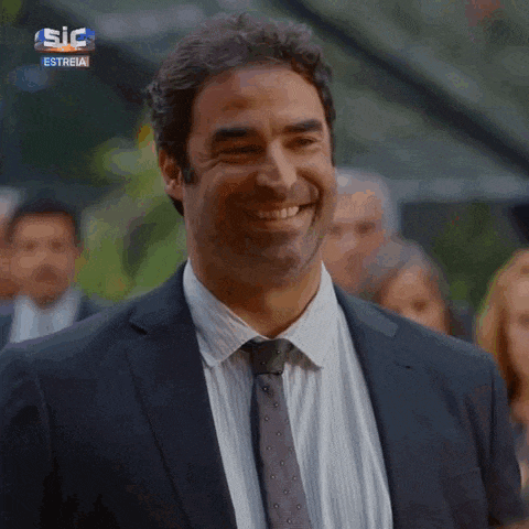 a man in a suit and tie is smiling in front of a sign that says ' sic estreia '