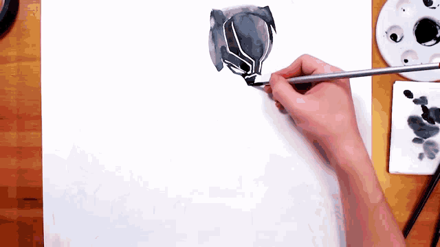 a person is painting a black panther with a brush on a piece of paper