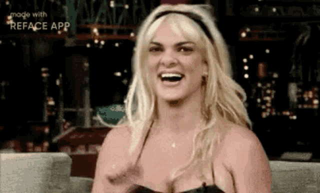 a blonde woman is sitting on a couch laughing and smiling .