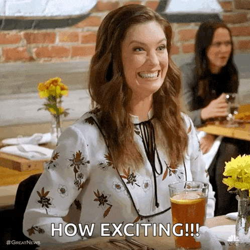 a woman is smiling while sitting at a table with a glass of beer and the words how exciting .