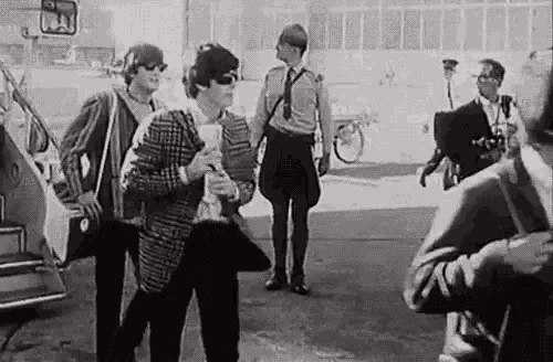 a black and white photo of a group of people standing next to each other in front of a car .