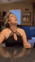 a woman in a black top is sitting at a counter looking up