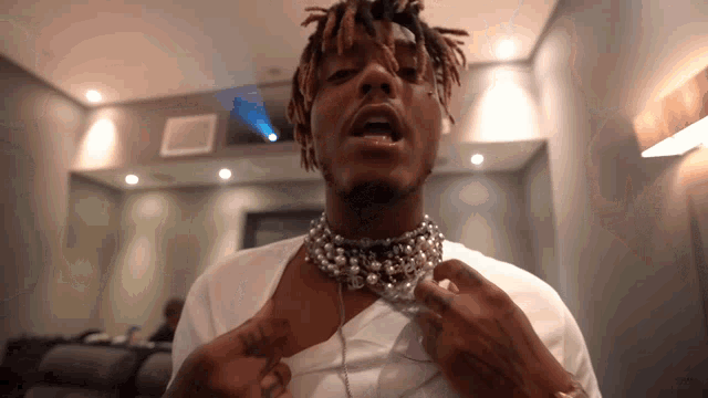 a man with dreadlocks and a pearl necklace around his neck