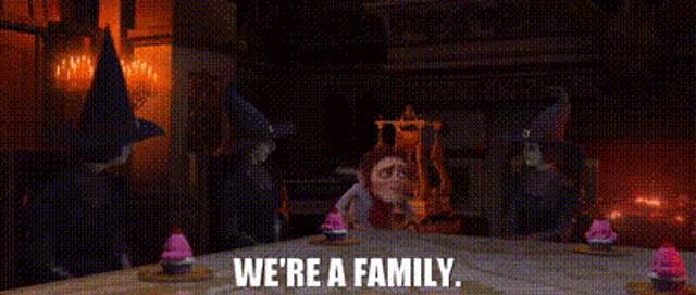 a group of gnomes are standing around a table with the words `` we 're a family '' written on the screen .