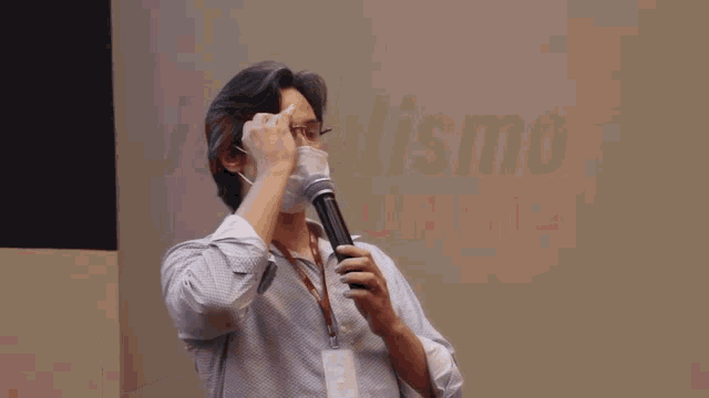 a man wearing a face mask holds a microphone