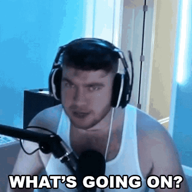 a man wearing headphones and a tank top is talking into a microphone .