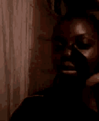 a close up of a woman 's face with a pink curtain in the background