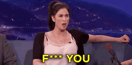 a woman is sitting in front of a microphone and saying f * * you .