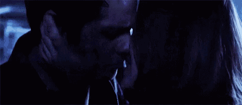 a man and woman are kissing in a dark room .