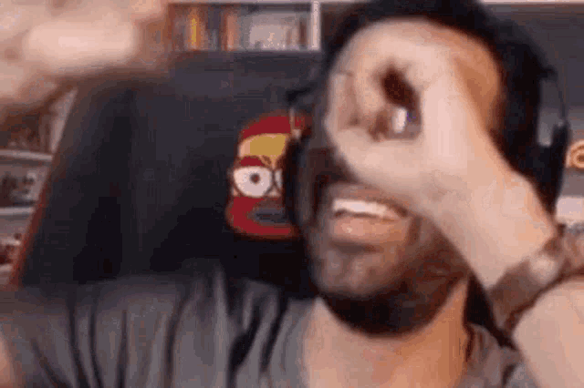 a man with a beard is making a funny face while wearing headphones and a hat .