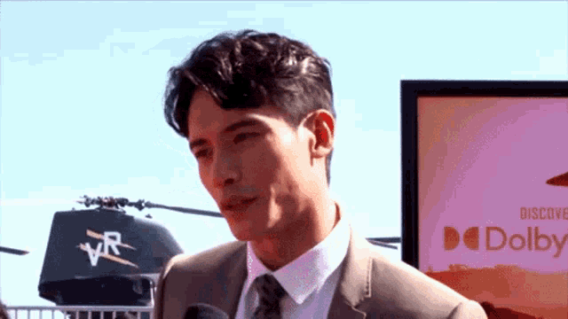 a man in a suit stands in front of a sign for dolby