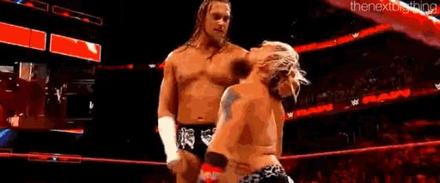 two wrestlers are wrestling in a wrestling ring while a crowd watches .