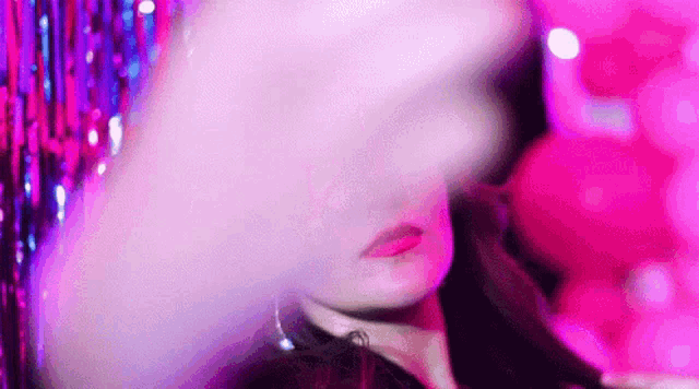 a close up of a woman 's face in front of a pink background .