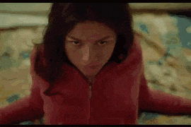 a woman in a red jacket is sitting on a bed .