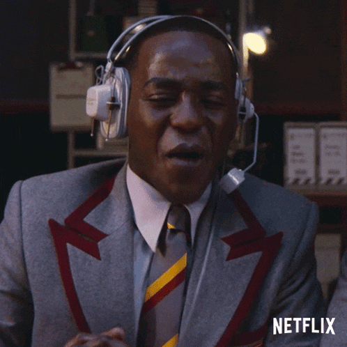 a man in a suit and tie is wearing headphones and a microphone with a netflix logo behind him