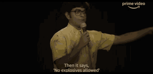 a man in a yellow shirt is holding a microphone and talking into it .