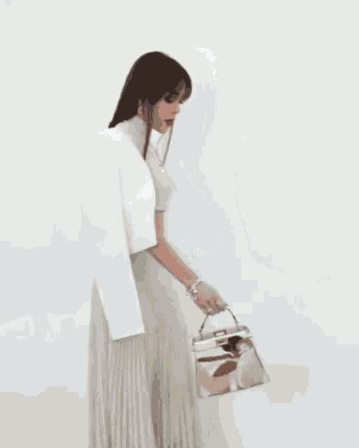 a woman wearing a pleated skirt and a crop top is holding a bag .