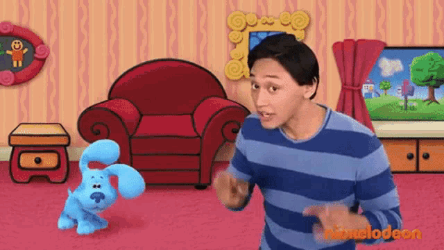 a man in a blue and white striped shirt stands next to a stuffed blue dog