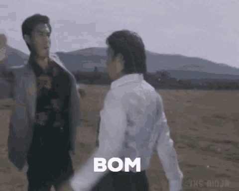 a couple of men are standing next to each other in a field holding hands .