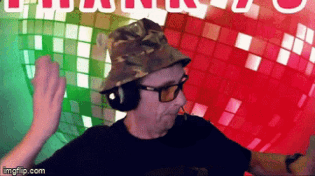 a man wearing a camouflage hat and sunglasses is dancing in front of a disco ball .