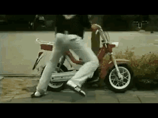 a man is riding a scooter down a sidewalk