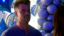a man is standing in front of a bunch of blue balloons and looking at a woman .