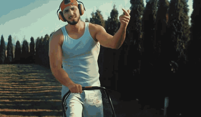 a man wearing headphones and a helmet is riding a lawn mower