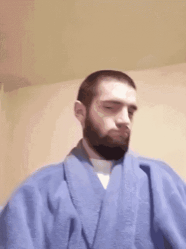 a man with a beard is wearing a blue robe and waving his hand .