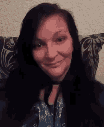 a woman with long black hair is smiling while sitting in a chair