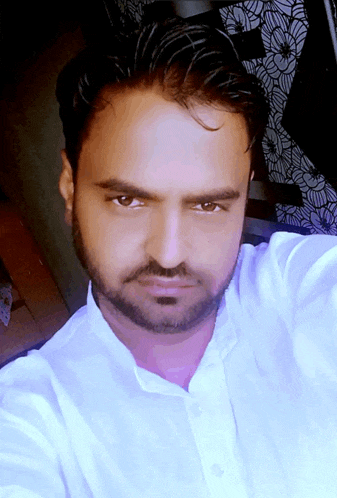 a man with a beard and a white shirt is taking a picture of himself