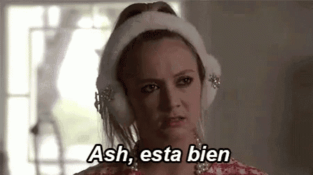 a woman wearing ear muffs is saying `` ash , esta bien '' in spanish .