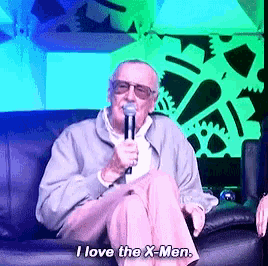 an older man is sitting on a couch holding a microphone and says i love the x-men