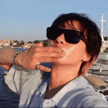 a person wearing sunglasses with a ring on their wrist