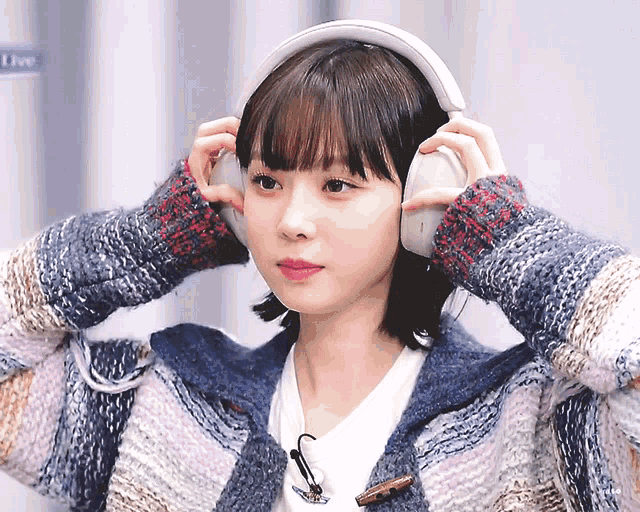 a woman wearing headphones looks at the camera