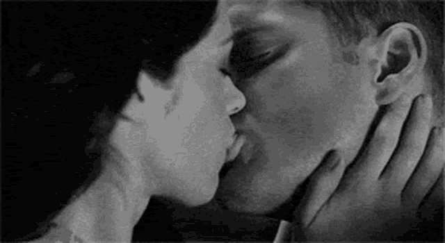 a man and a woman are kissing each other in a black and white photo .